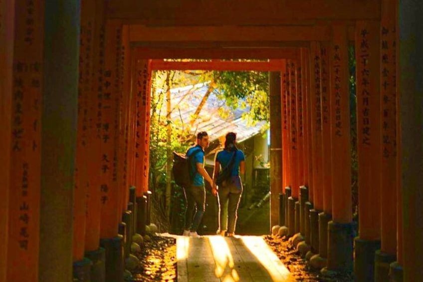 A shrine entrance with two people walking through, surrounded by traditional Japanese torii gates. 4