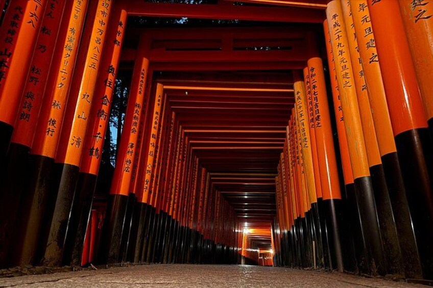 A corridor lined with orange torii gates leading to a shrine. 1