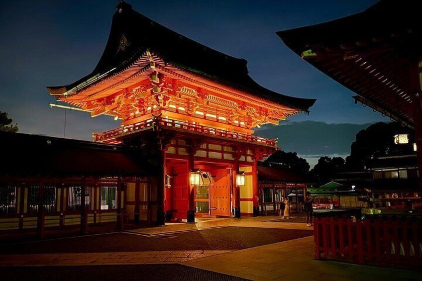 A traditional Japanese gate with red lanterns, surrounded by buildings with wooden structures and a paved walkway. 2