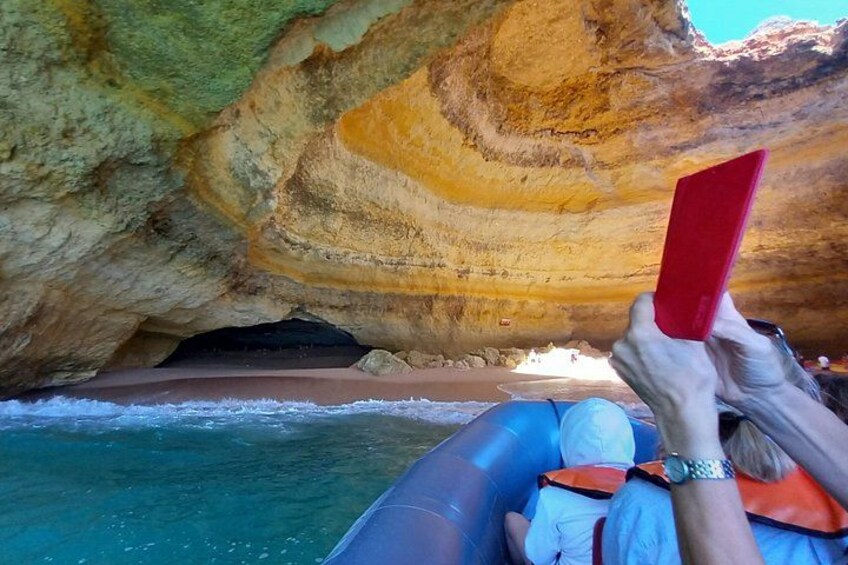 Eine Person in einem Floß auf einem Fluss, hält ein rotes Objekt, im Hintergrund ein felsiger Felsen. 1