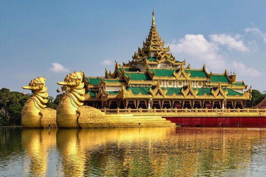 A traditional temple with golden roofs and lion statues by the water. 5