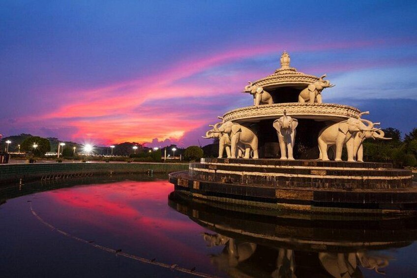A temple with elephants and a reflection in the water at dusk. 3