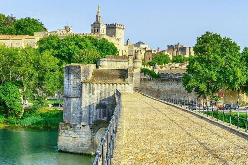 Un pont de pierre enjambant une rivière, avec un château en arrière-plan et des arbres le long de la rive. 4