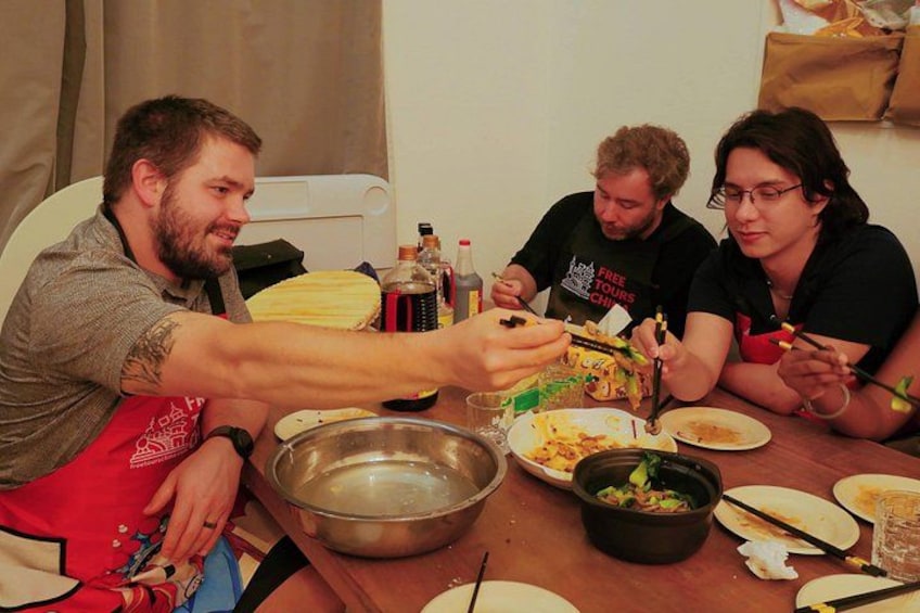 Cuatro personas sentadas en una mesa con comida, bebidas y un bol. 2