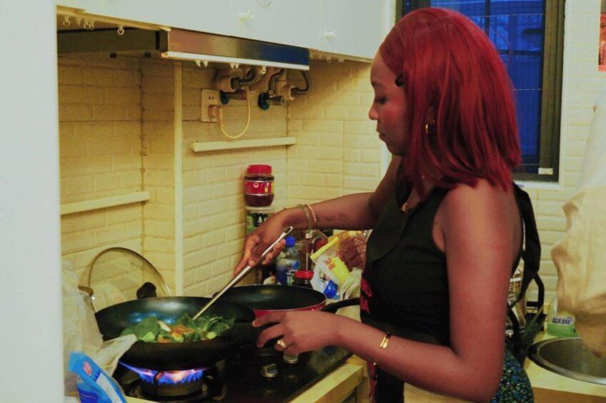 Una persona cocinando con un wok en una hornilla. 4