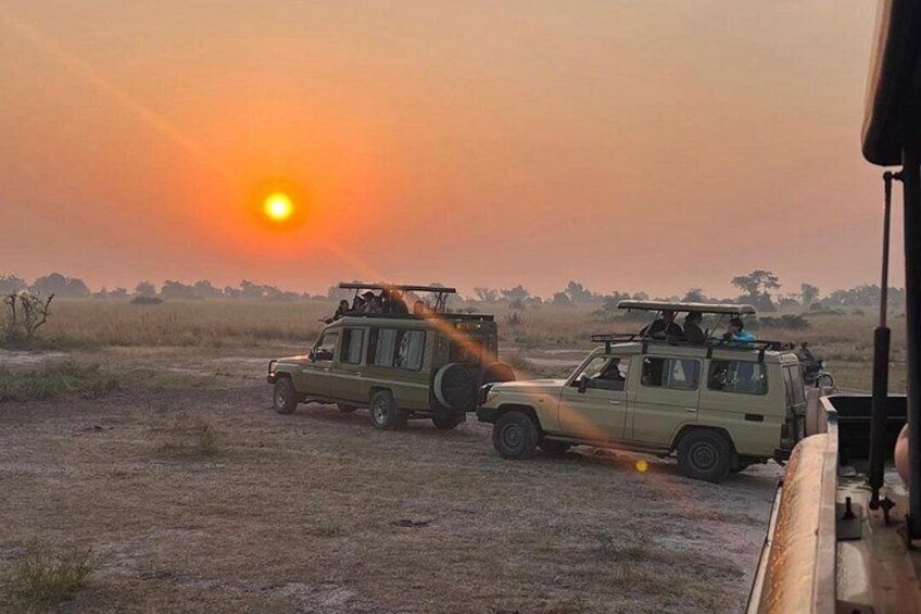 Two safari vehicles on a dirt road during sunset. 3