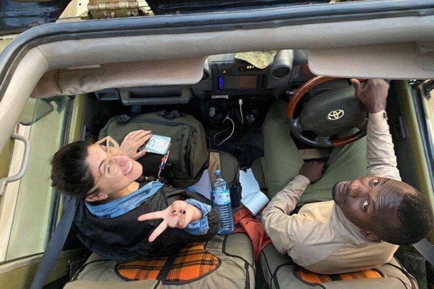 A vehicle interior with two people, one holding a smartphone and the other making a peace sign. 2