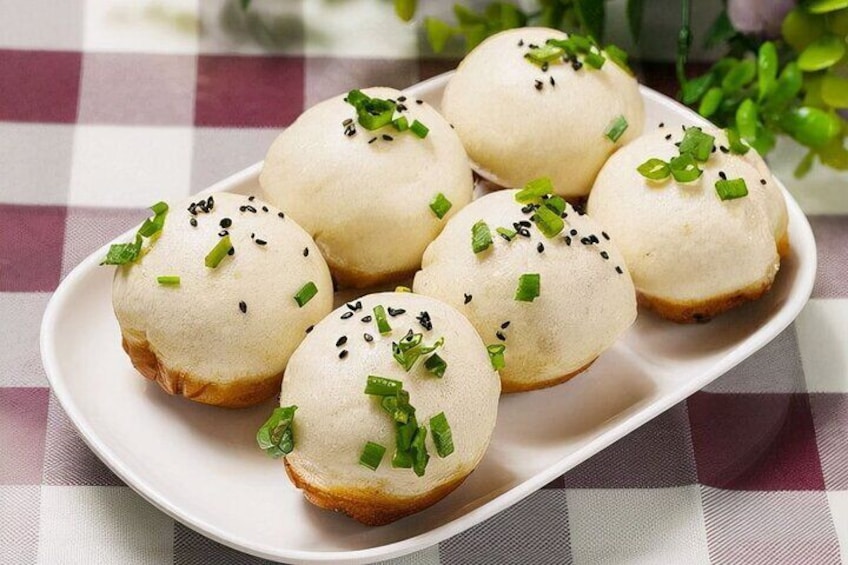A plate of six baozi buns garnished with sesame seeds and chopped green onions. 5