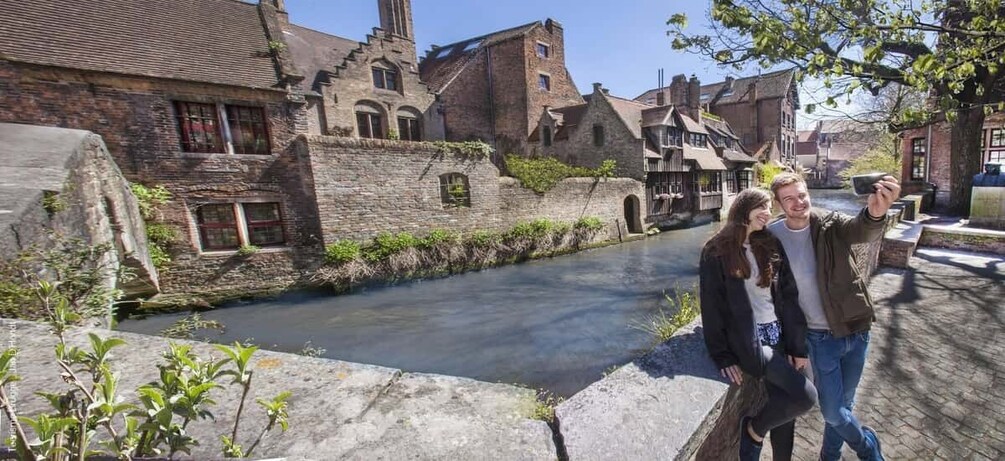 A historic stone bridge over a canal with old buildings and a tower. 1