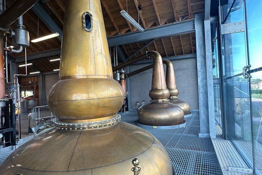 A distillery with large copper stills and a glass building. 2