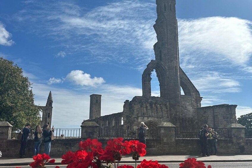 A historic stone structure with arches and towers, surrounded by red flowers. 4