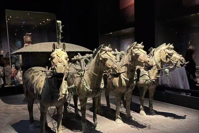A display of ancient chariots with horses in a museum. 3