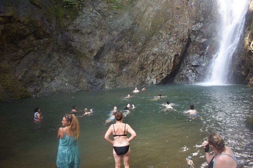 A waterfall, people swimming, and rocky cliffs. 4