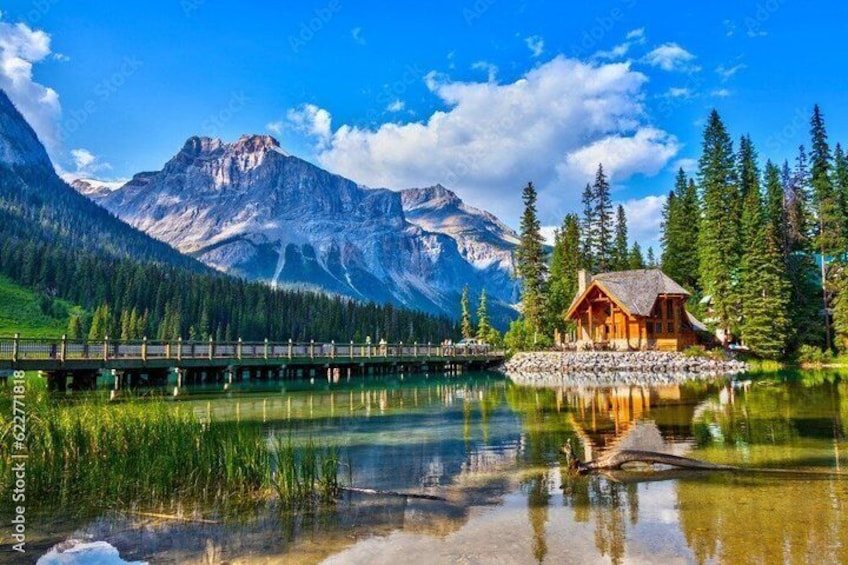 A wooden cabin by a lake with mountains in the background. 3