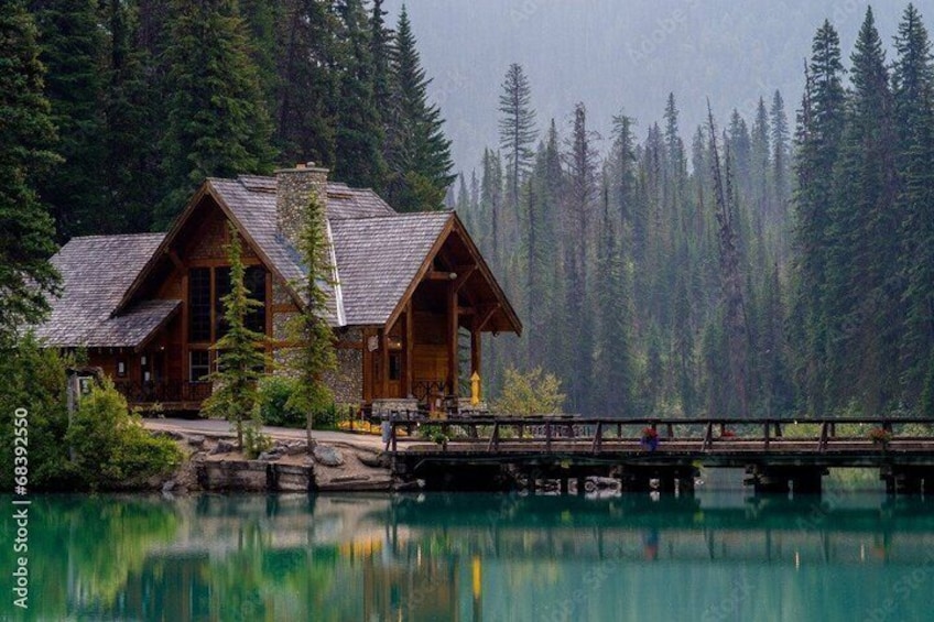 A wooden cabin by a lake with a dock extending into the water. 2