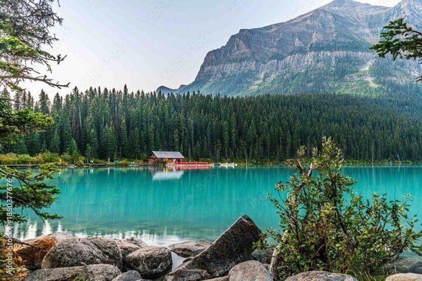 A turquoise lake with a cabin, surrounded by dense forest and mountains. 4
