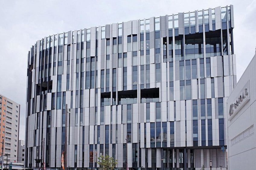 Un edificio moderno con una fachada singular de paneles verticales y grandes ventanales. 2