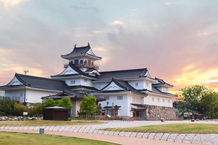 Un castillo japonés tradicional con varios edificios, un muro de piedra y un cielo despejado. 5