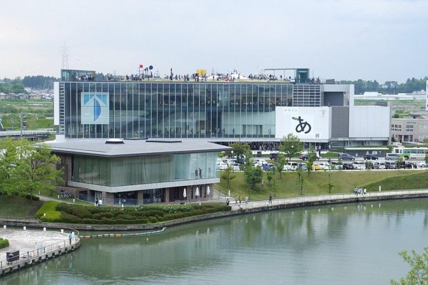 Un edificio moderno con fachada de vidrio, un logotipo grande y una masa de agua al frente. 3