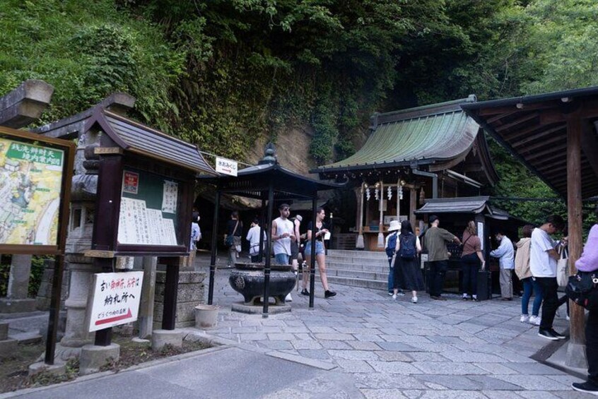 A traditional Japanese shrine with visitors, stone lanterns, and signage. 4