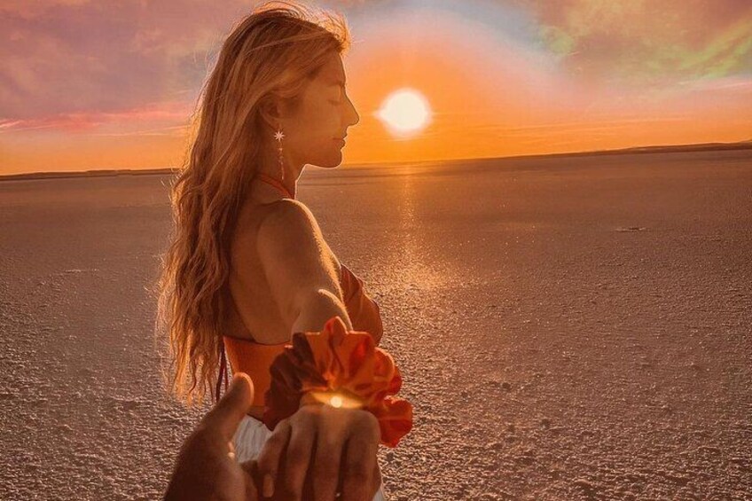 Eine Person hält eine Blume in der Nähe des Wassers bei Sonnenuntergang. 2