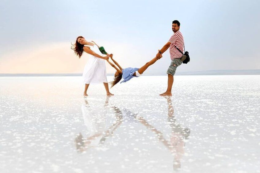 A couple on a reflective salt flat with a clear sky. 1
