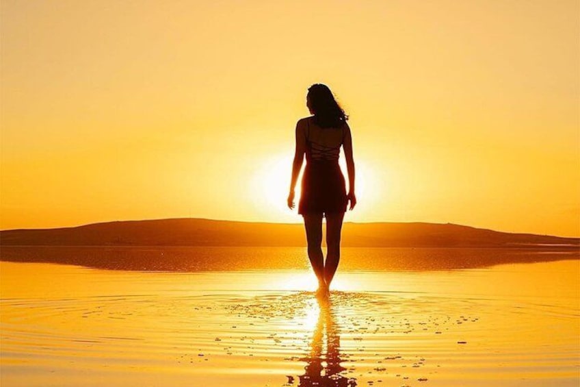 A person walking on a beach at sunset. 5