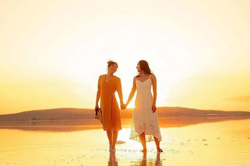 Two people holding hands on a beach at sunset. 3
