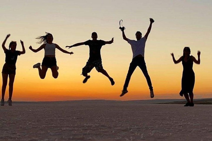A group of people jumping in silhouette against a sunset. 3