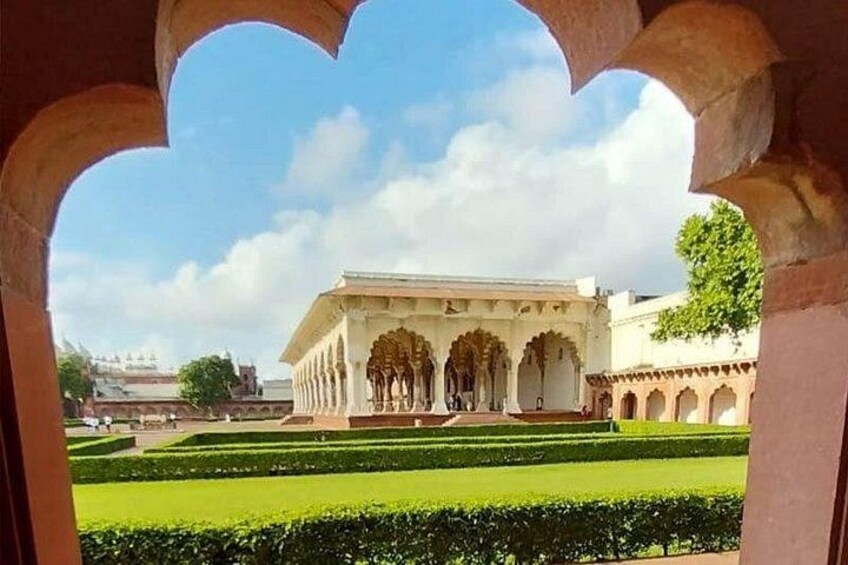 A historic building with arches and a well-maintained garden. 4