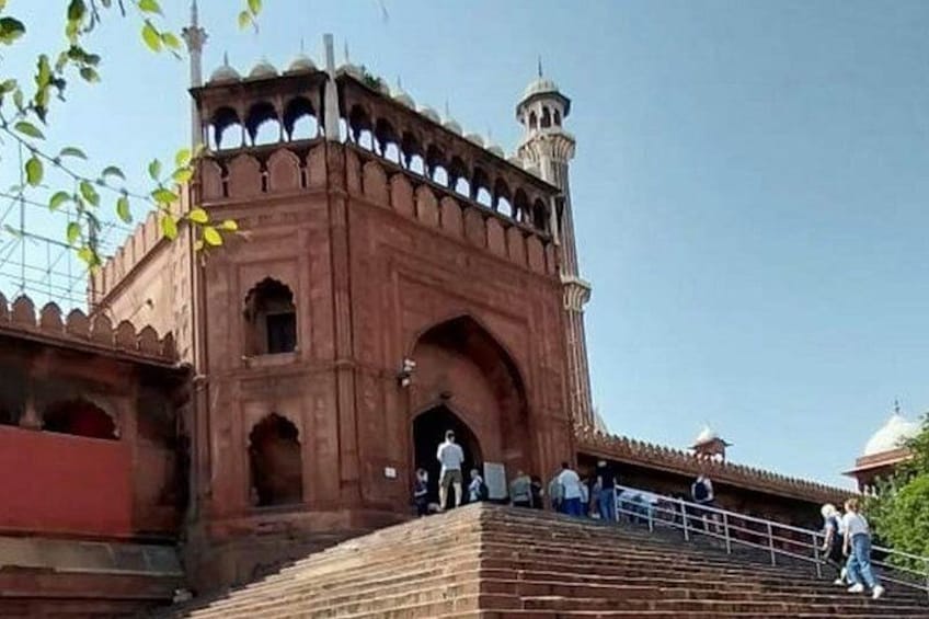 A large, historic building with a prominent archway and a minaret. 1