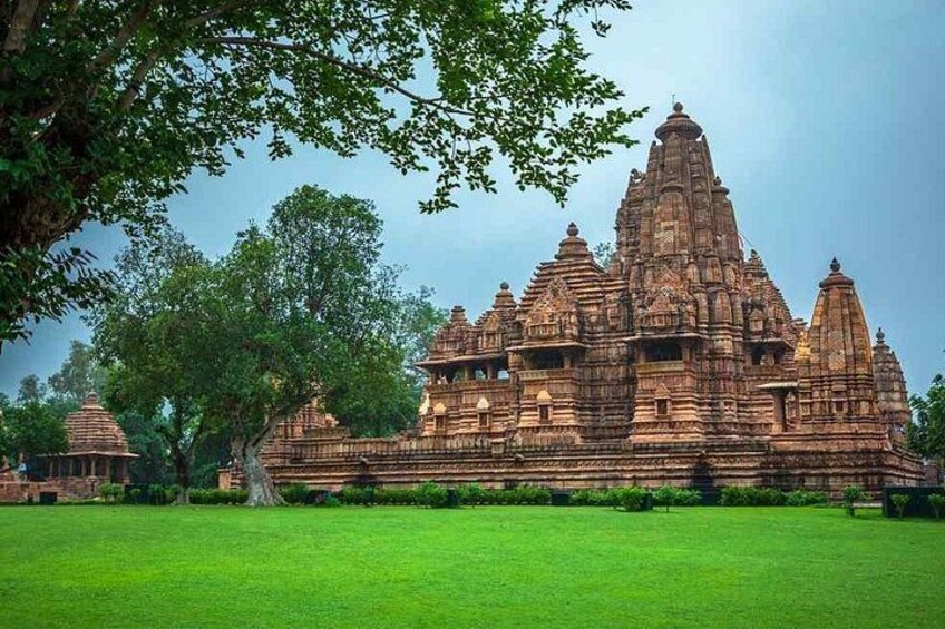 A large, intricately designed temple complex with multiple spires and detailed carvings, surrounded by a lush green lawn. 2