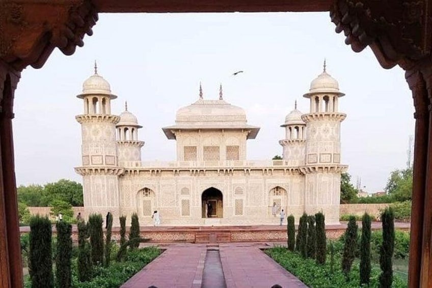 A historic building with two domes and a central archway, surrounded by neatly trimmed greenery. 5