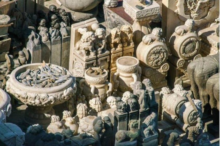 A collection of ancient stone sculptures and artifacts, including figures, animals, and decorative elements, displayed in an outdoor setting. 5