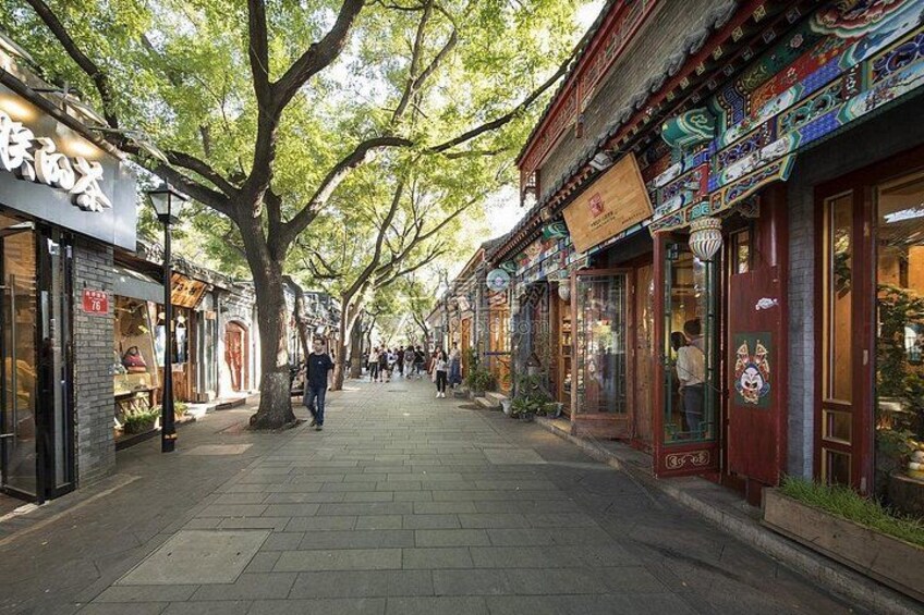 A tree-lined pedestrian street with traditional architecture and shops. 2