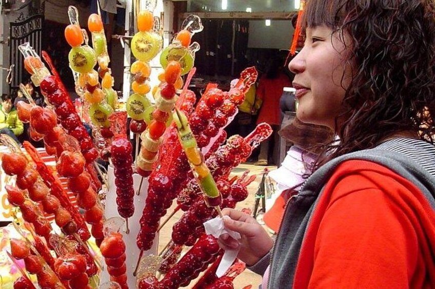 A person holding a skewer with various fruits. 4