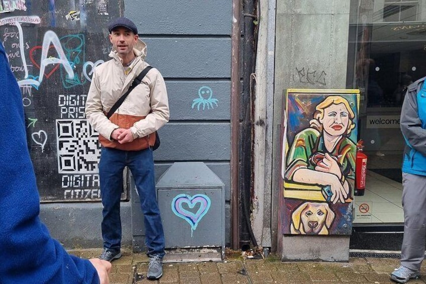 Eine Person steht vor einem Gebäude mit Graffiti und einem Wandgemälde. 2