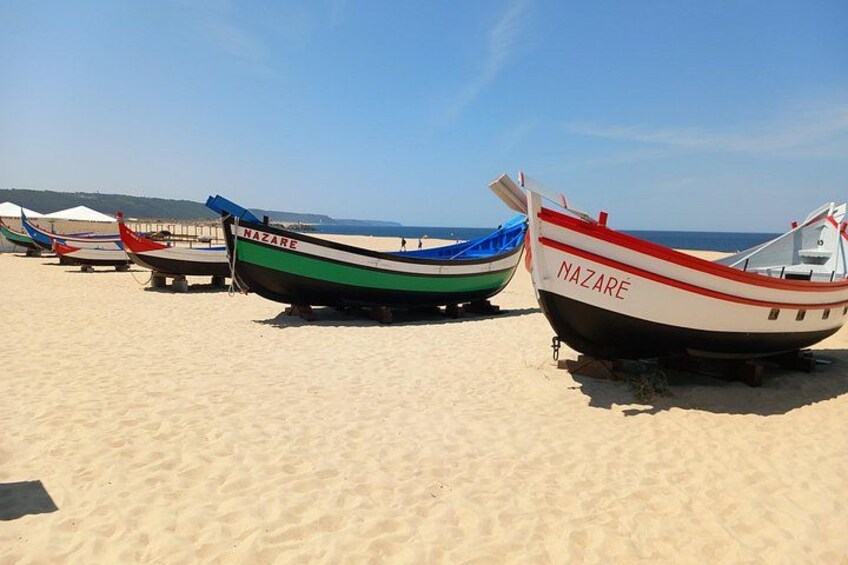 Several boats on a sandy beach with the ocean in the background. 5