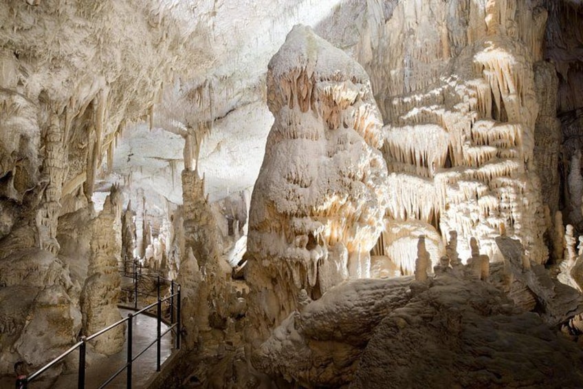 Una grotta con stalattiti e stalagmiti, una ringhiera metallica e una grande formazione rocciosa. 2