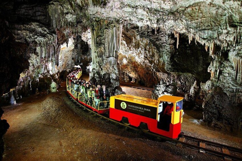 Un treno con passeggeri che viaggia attraverso una grotta con stalattiti. 1