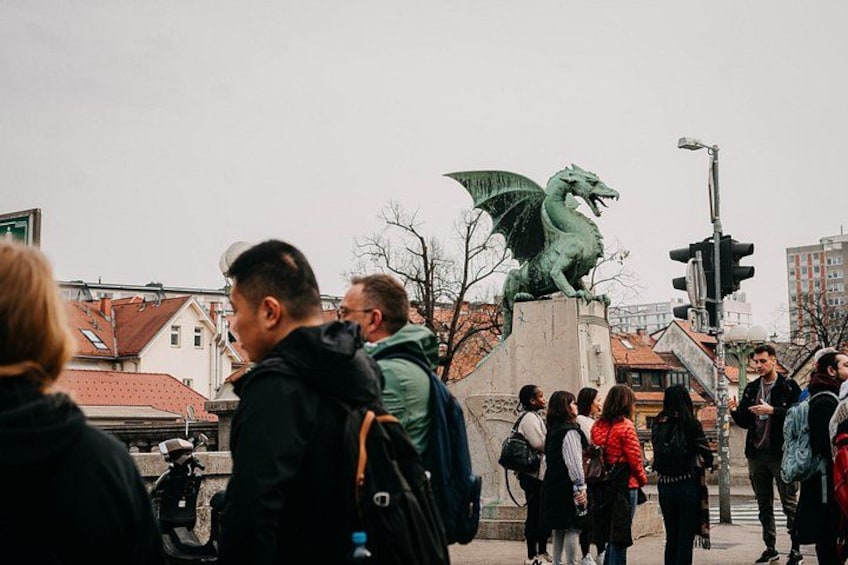 Un gruppo di persone si è riunito attorno a una statua di un drago in un contesto urbano. 5
