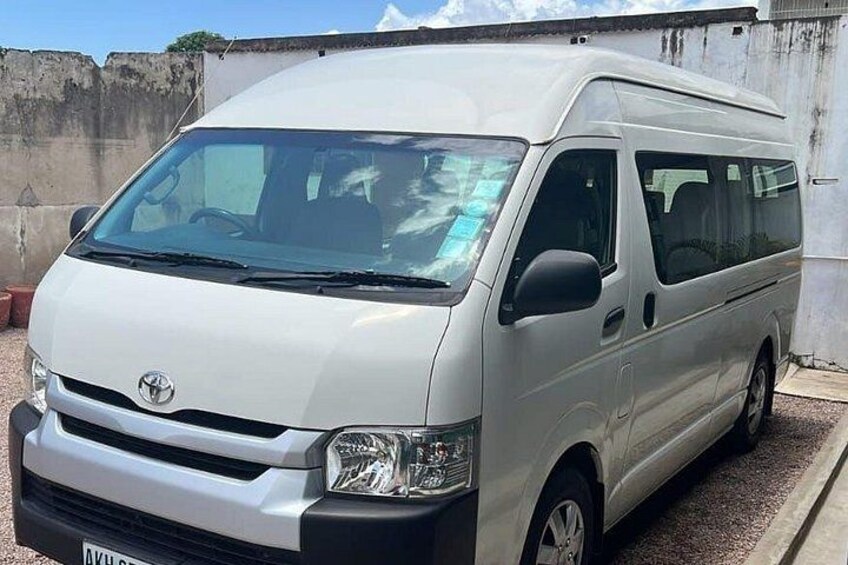 A white Toyota van parked in front of a concrete wall. 3