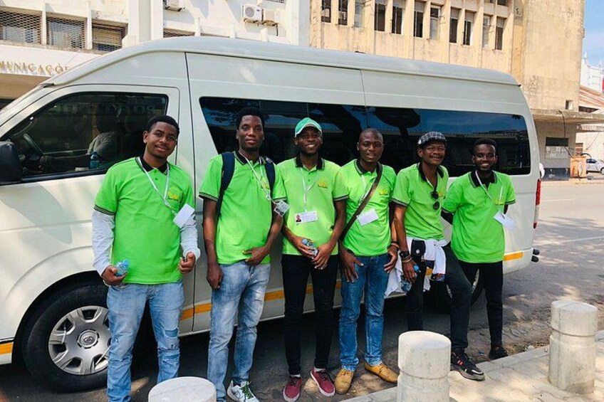 Five people in green shirts standing in front of a white van. 5