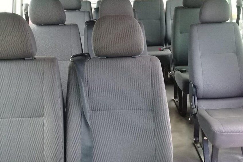 Rows of grey upholstered car seats with headrests and seat belts. 2