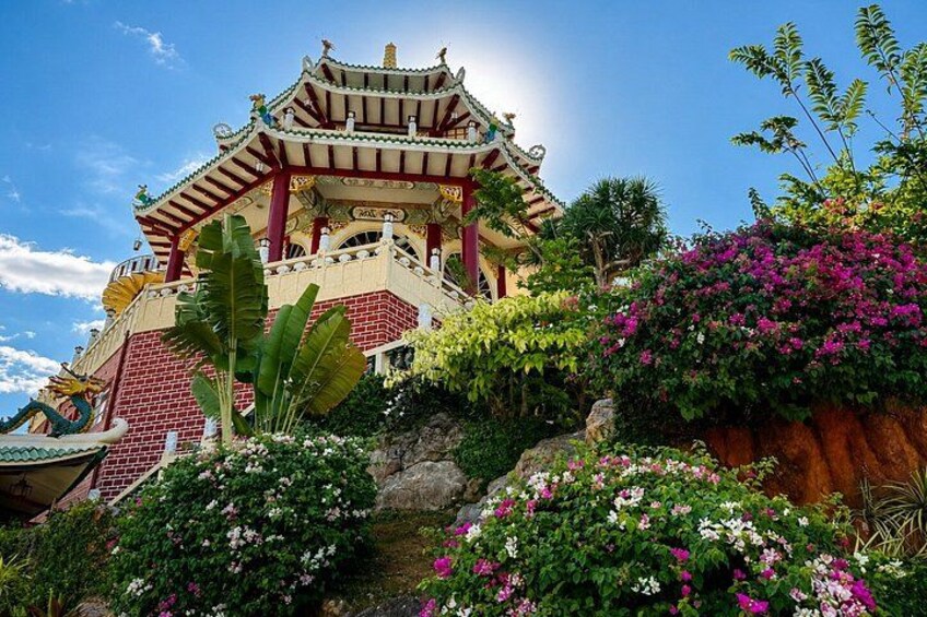 A traditional Chinese temple with ornate architecture, surrounded by lush greenery and flowering plants. 1