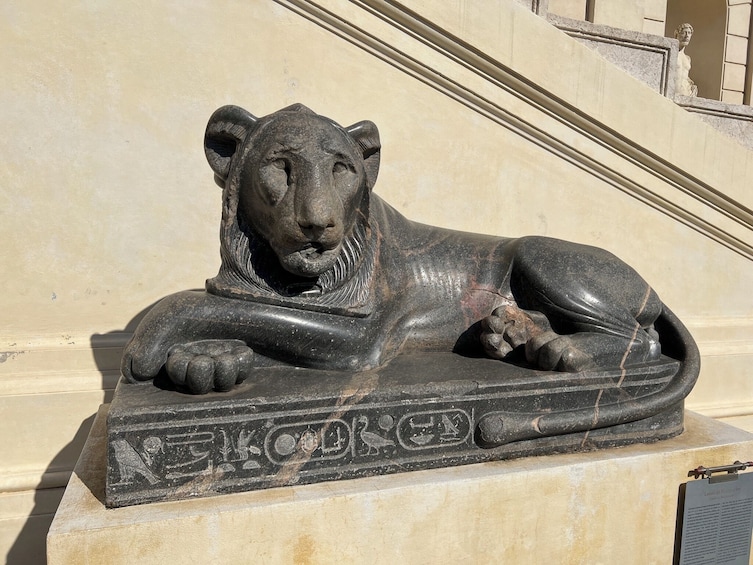 A stone sculpture of a reclining lion on a pedestal. 4