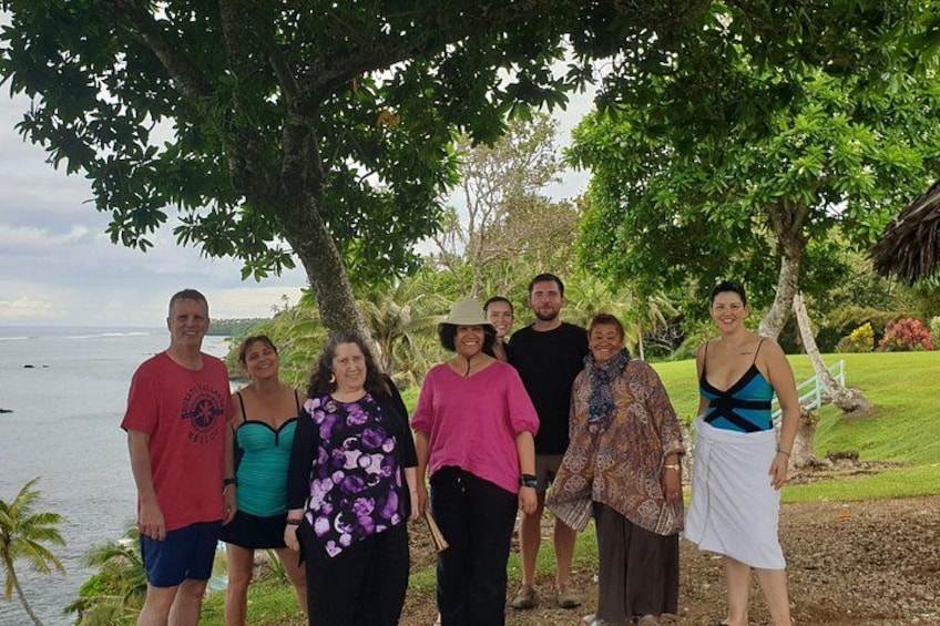 A group of people standing under a tree by a body of water. 5