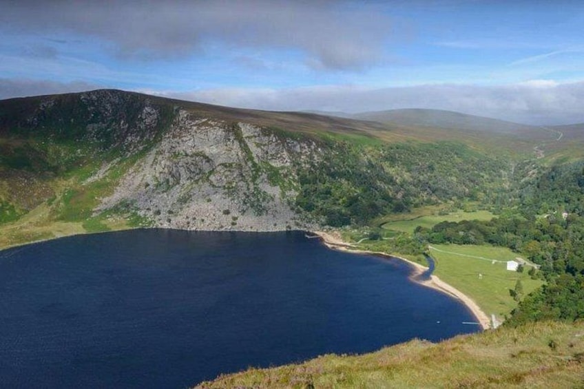 A lake surrounded by hills, a small building, and a winding road. 1