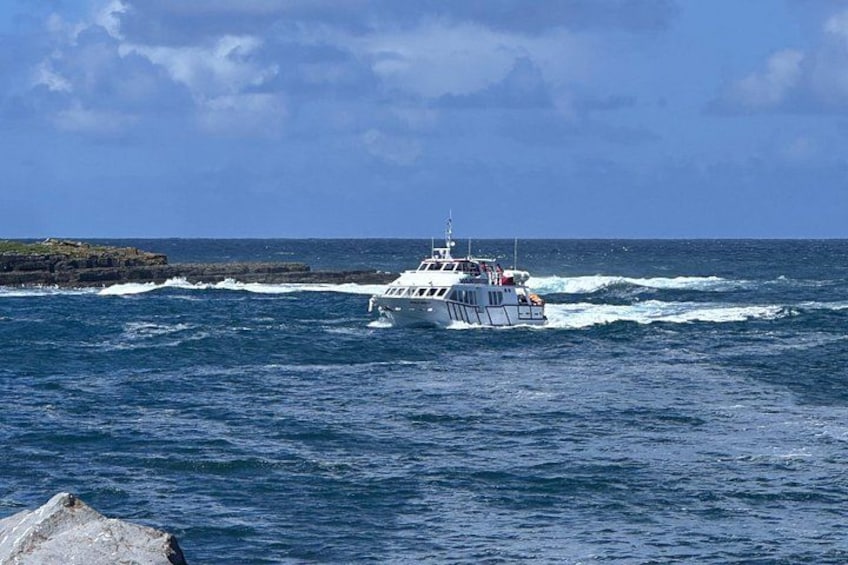 Ein weißes Boot mit rotem Streifen an der Seite, das sich durch aufgewühltes Meer bewegt. 2