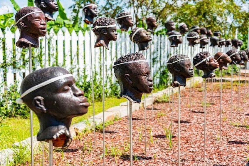 Une rangée de sculptures de têtes dans un jardin. 1
